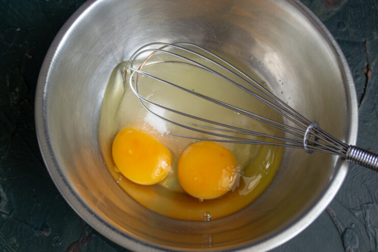 Preparing the Egg Base Whisking eggs with sugar and salt in a metal bowl