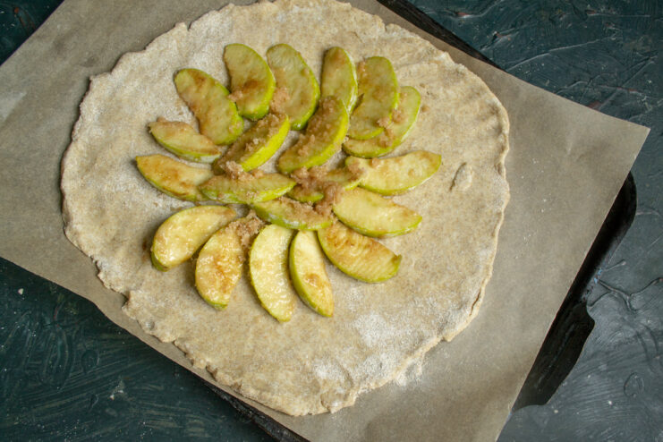 Arranging the Apples Apple slices arranged in a circular pattern on dough