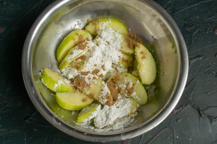 Spicing the Filling Apples tossed with cinnamon and starch in a bowl