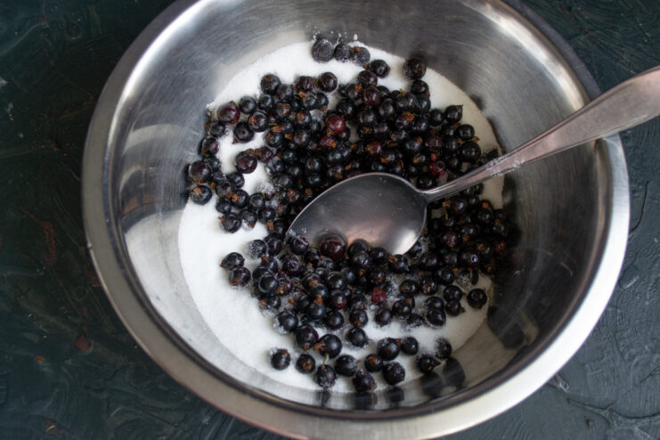 Mixing Berries With Sugar Fresh blackcurrants mixed with white sugar in a deep glass bowl