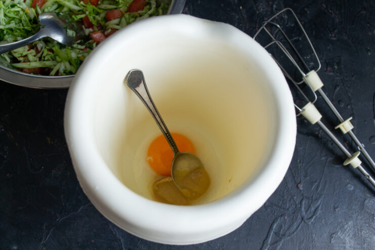 Starting the Homemade Sauce Bright egg yolk and mustard in a mixing cup ready for making homemade mayonnaise.