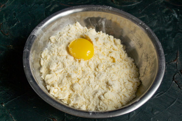 Adding egg yolk and ice water to the dough Egg yolk placed in the center of the butter and flour crumbs for kneading