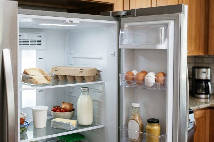 Eggs Stored In Refrigerator Door Chicken eggs sitting in plastic trays attached to the inside door of an open refrigerator.