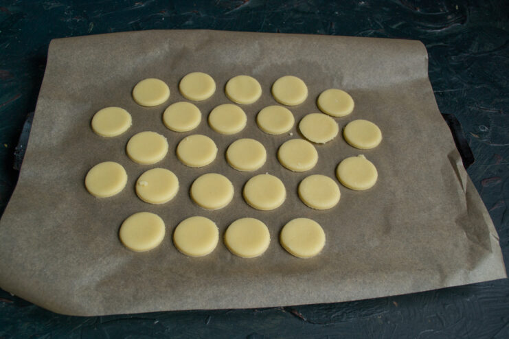 Cookies Before Baking Unbaked round cookie cutouts arranged on a parchment-lined baking sheet