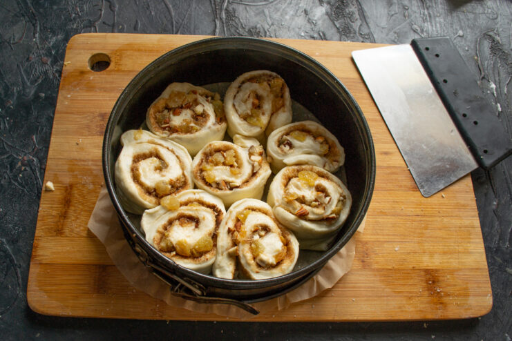 Arranging dough in the pan Arranging cut dough slices into a flower pattern inside a parchment-lined baking pan