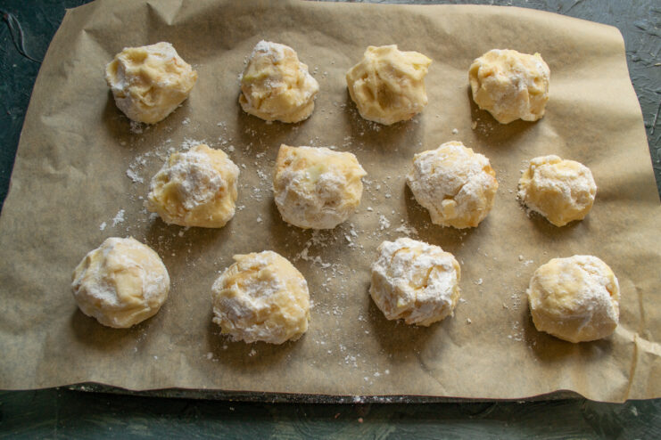 Shaping the dough balls Round scone dough balls coated in powdered sugar on a baking sheet