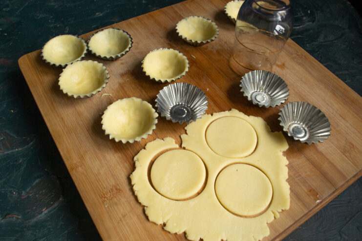 Pressing the dough into metal molds Dough blanks pressed into fluted metal tartlet molds