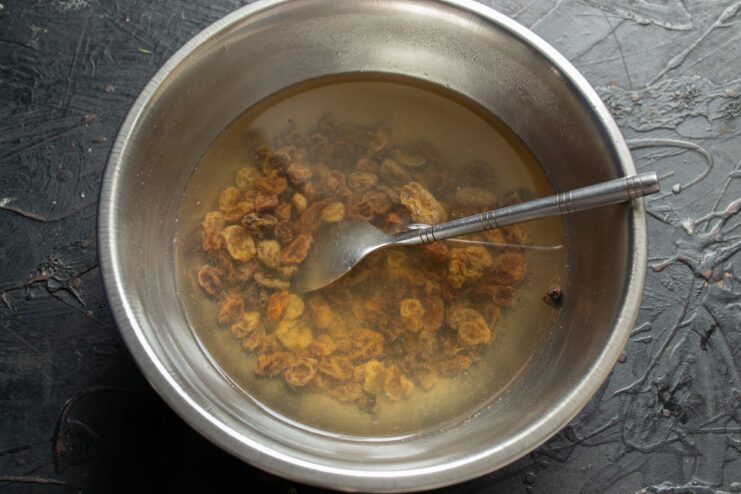 Preparing the raisins Soaking raisins in a metal bowl filled with hot water