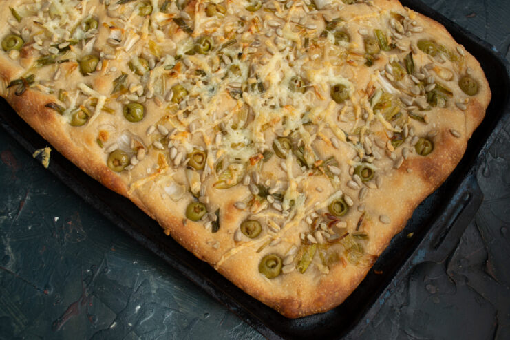 Focaccia out of the oven Baked focaccia with melted cheese on a baking sheet