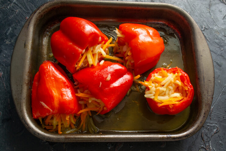Peppers after baking Baked and softened stuffed red bell peppers in a roasting pan