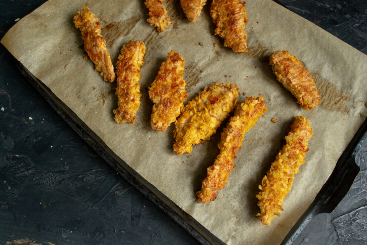 Baked chicken strips straight from the oven Golden crispy chicken strips freshly baked on a baking sheet