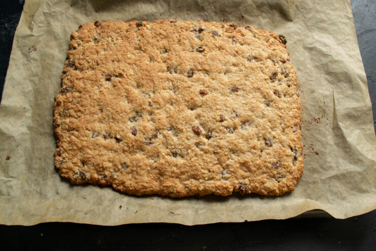 Baking the cookie slab Baked golden brown cookie slab resting on parchment paper