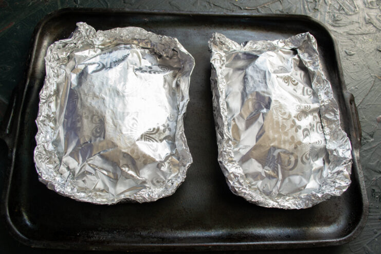 Prepping for the oven Fully assembled and sealed aluminum foil packets on a tray