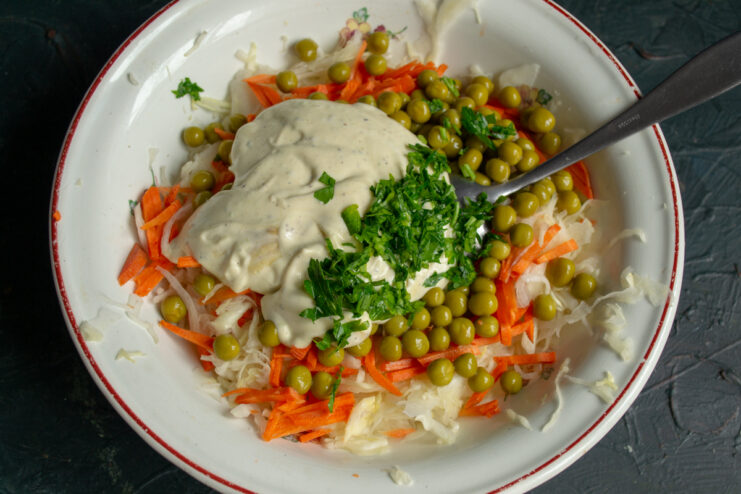 Adding dressing to vegetables Zesty dressing, minced garlic, and fresh parsley added on top of mixed vegetables