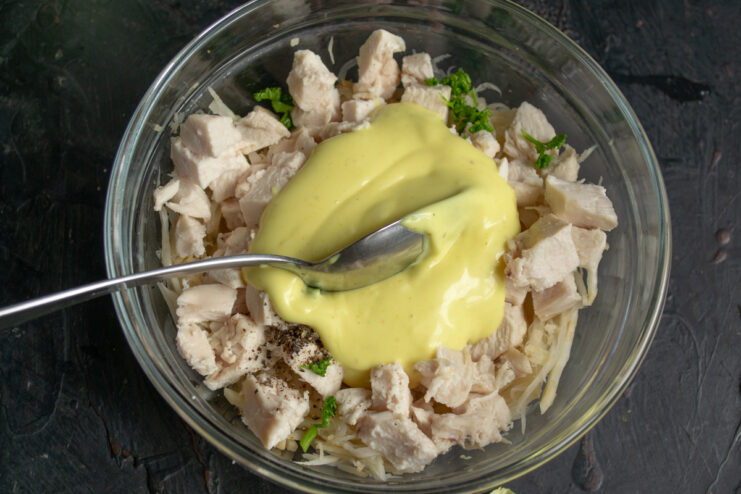 Dressing the salad Pouring thick homemade mayonnaise dressing over chicken and celeriac