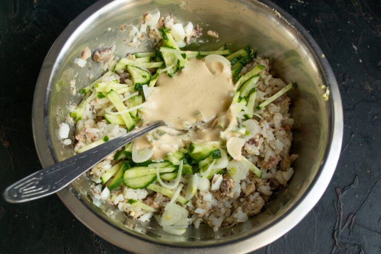 Dressing the salad Pouring homemade mayonnaise dressing over the salad ingredients in a bowl