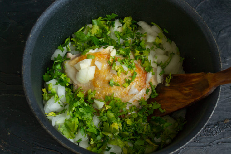 Adding Fresh Herbs Parsley and celery leaves simmering with chicken in a pot