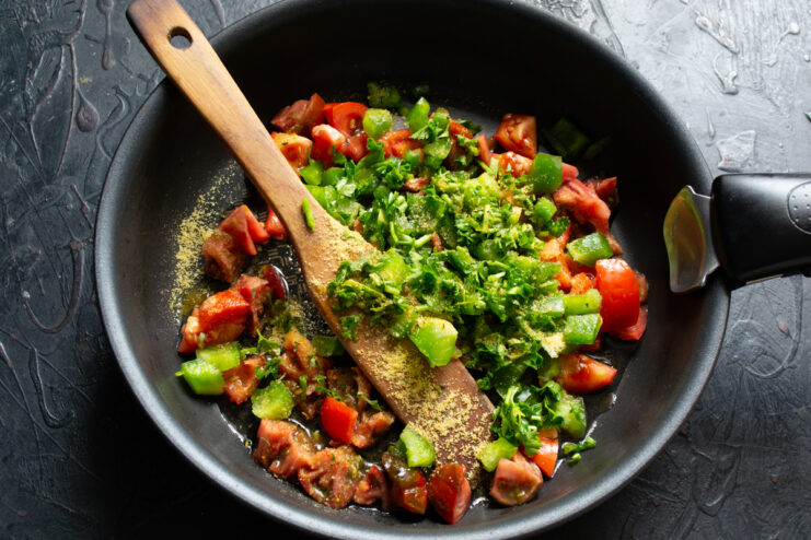 Fresh parsley and spices mixed with sautéed vegetables in a pan