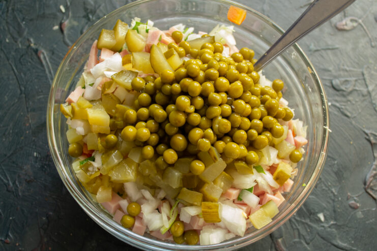 Traditional Olivier ingredients Green peas and diced pickles in a salad bowl