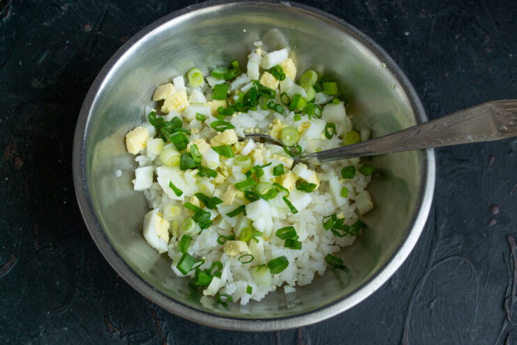 Chopped scallions mixed into a bowl with rice and eggs