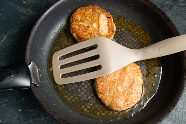 Pan-frying the fish patties Frying round salmon patties in a skillet