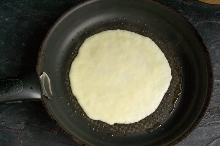 Cooking a thin layer of zucchini crepe batter in a skillet