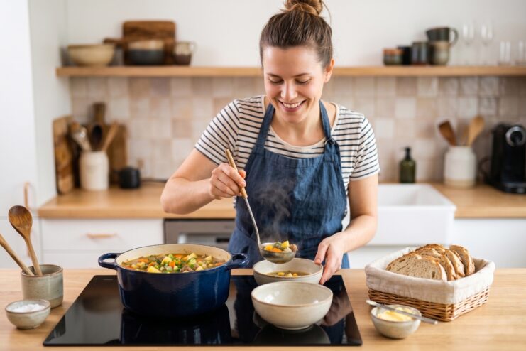 Serving a Perfectly Seasoned Dish A woman ladling a hot, richly colored vegetable soup from a pot into a ceramic dining bowl