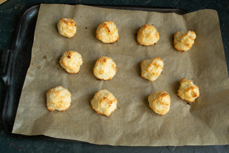Freshly baked golden coconut macaroons. Golden baked coconut macaroons sitting on a baking sheet straight from the oven.