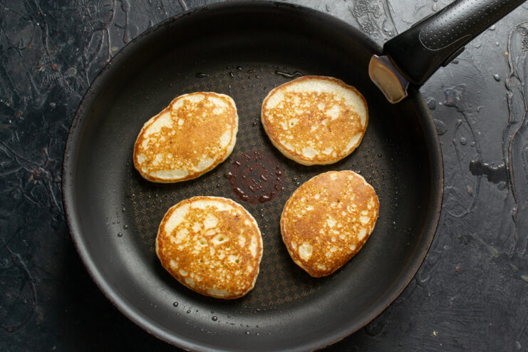 Flipped golden brown pancakes frying in a skillet