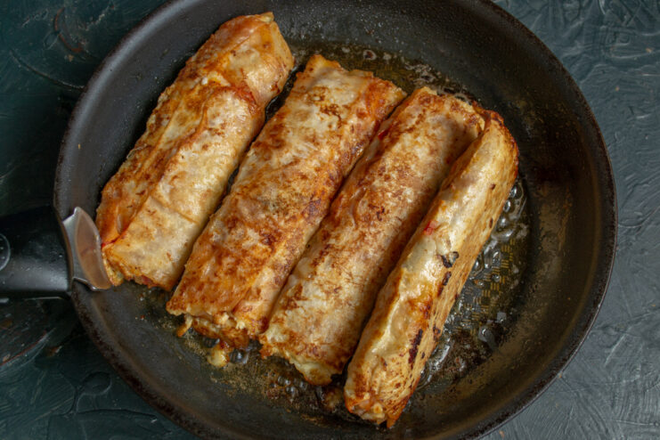Frying lahmacun rolls in a skillet until deep golden brown