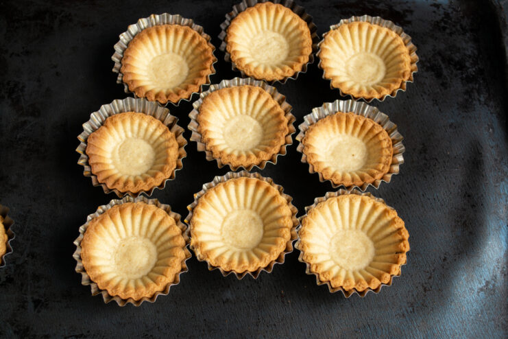 Baked tartlet shells Golden baked shortcrust pastry shells in metal molds