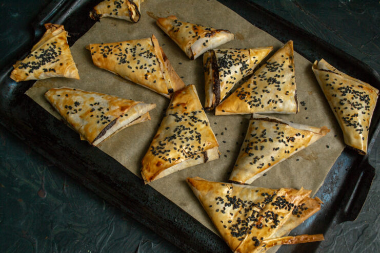 Baked Samosas Golden brown baked samosas resting on a sheet of parchment paper