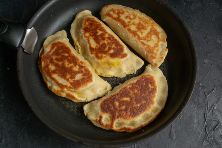 Finishing the hand pies under a lid Crispy golden hand pies cooking in a covered skillet