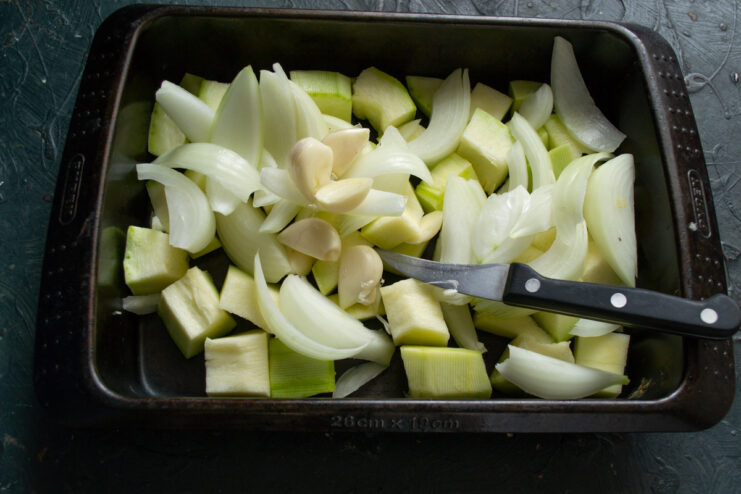 Adding garlic for flavor Halved garlic cloves added to the vegetables in the pan