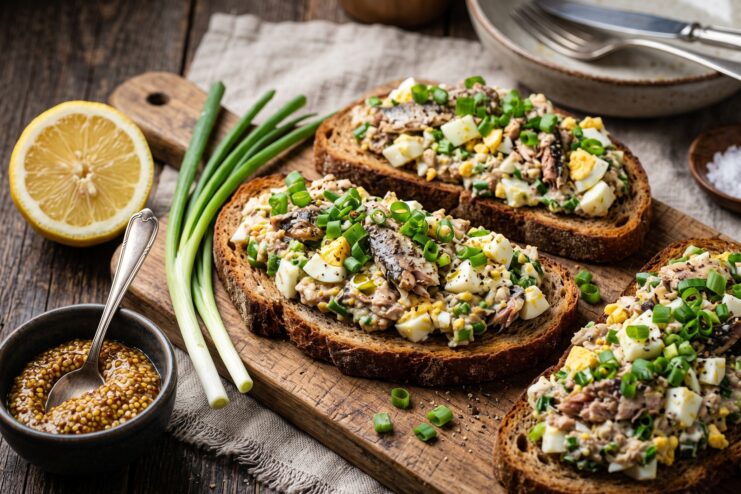 Appetizing toasts topped with a spread of canned sardines, boiled egg, and green onions