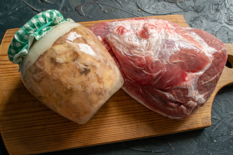 Ingredients and finished product Jar of homemade canned meat next to fresh raw pork