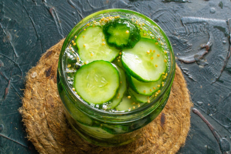 Pouring the Marinade Glass jar with cucumbers being filled with hot marinade and mustard seeds