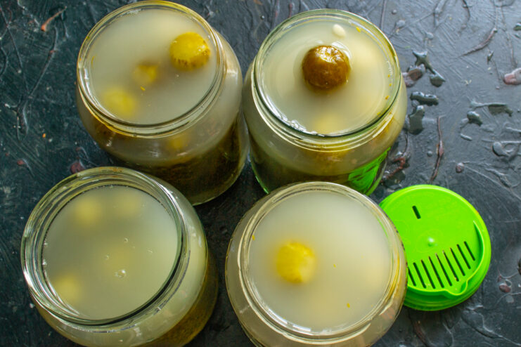 Final brine pour and pasteurization Glass jars filled with cucumbers and hot brine ready for pasteurization
