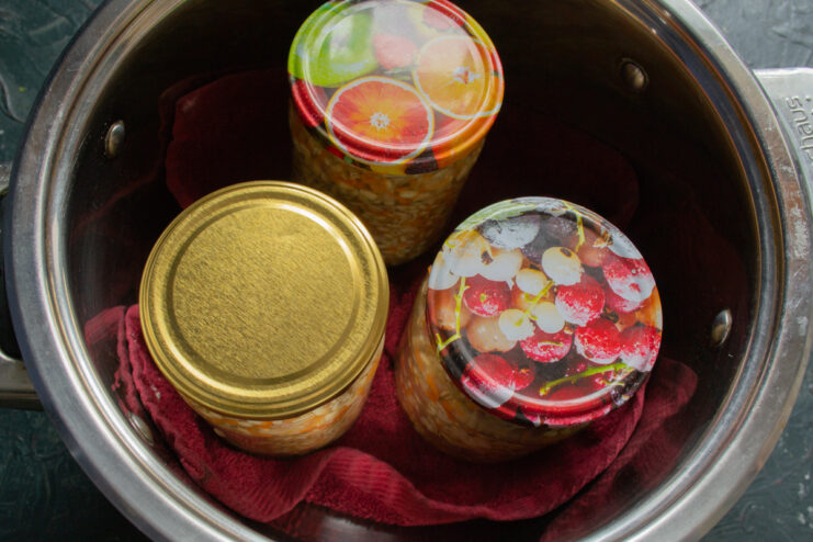Prepping for sterilization Sealed jars standing on a cloth towel inside a large pot