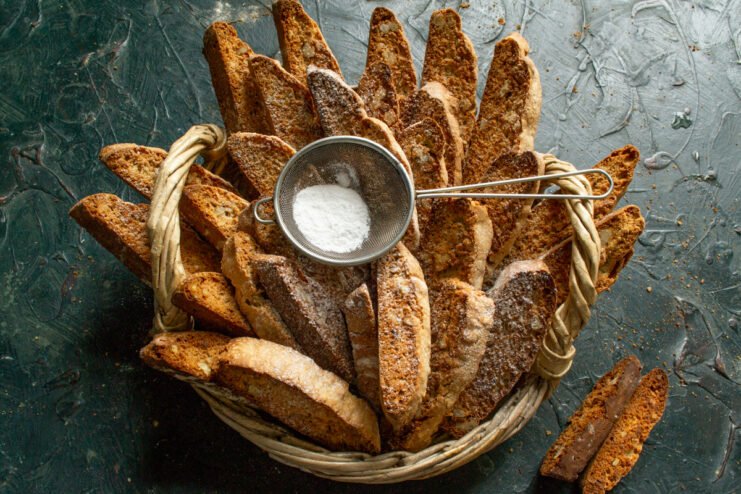 Decorating the pastry Dusting biscotti in a basket with powdered sugar through a sieve