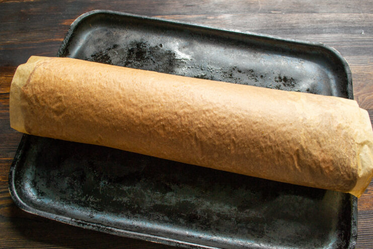 Rolling the hot sponge cake Chocolate sponge cake rolled up together with baking parchment.