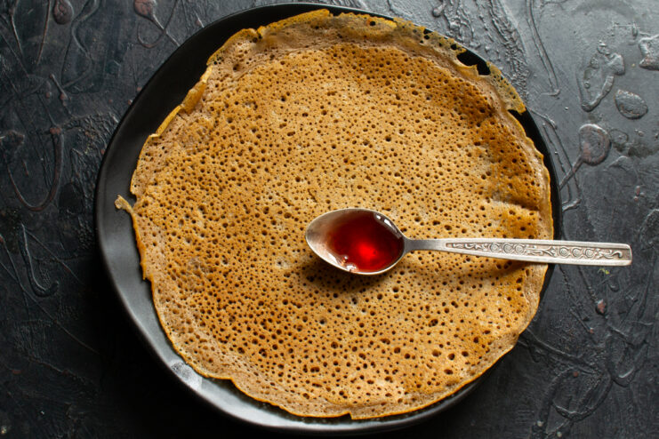 Drizzling hot crepes with syrup Drizzling strawberry syrup over a hot chocolate crepe