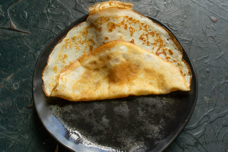 Folding hot crepes in half Folding a freshly cooked hot crepe in half on a plate