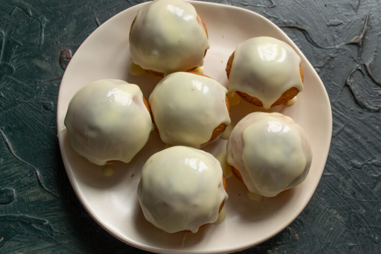 Glazing the Buns Pouring rich buttercream glaze generously over freshly baked buns