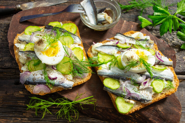 Sandwiches with salted Baltic herring, hard-boiled egg, and fresh herbs
