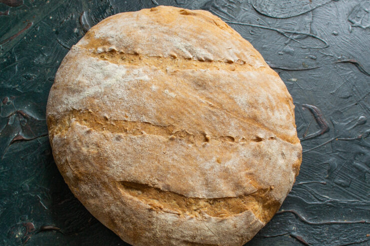 Finished Whole Wheat Bread A whole loaf of baked whole wheat bread against a dark background.