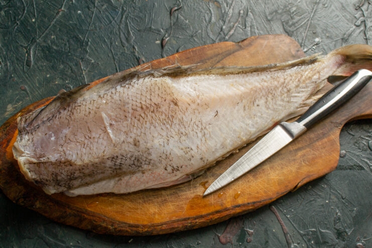 Preparing the cod Whole cod on a wooden cutting board