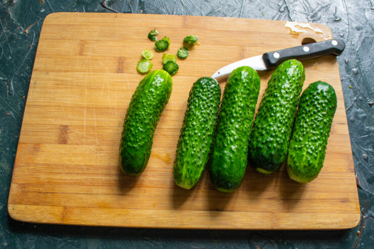 Preparing Cucumbers for Pickling Whole fresh cucumbers on a wooden board with trimmed ends