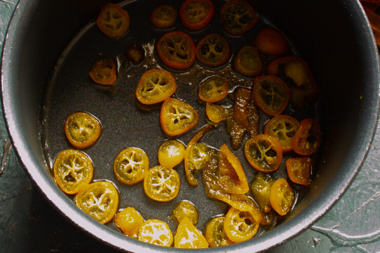 Making Kumquat Decoration Sliced kumquats simmering in a saucepan of sugar syrup