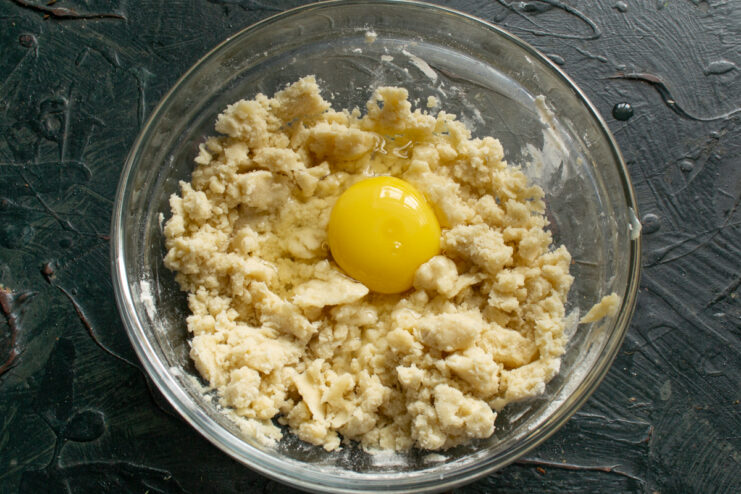 Incorporating The Egg Adding a whole cracked chicken egg into the crumbly dough mixture